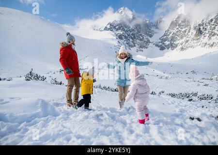 La jeune famille profite des vacances d'hiver dans les montagnes, jouant dans la neige, ayant un combat de boules de neige. Banque D'Images