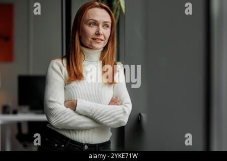 Femme professionnelle se relaxant par fenêtre de bureau Banque D'Images