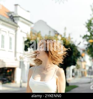 Femme avec des cheveux coulant dans le vent sur une journée ensoleillée animée dans la ville Banque D'Images
