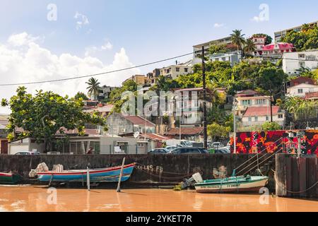 Fort-de-France, Martinique - 3 janvier 2018 : des maisons colorées gravissent la colline surplombant un port calme, où sont amarrés de petits bateaux de pêche. Banque D'Images