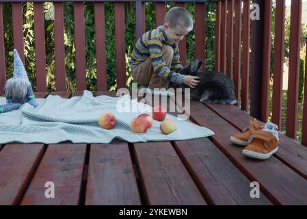 Garçon et lapin jouissant d'une terrasse ensoleillée Banque D'Images