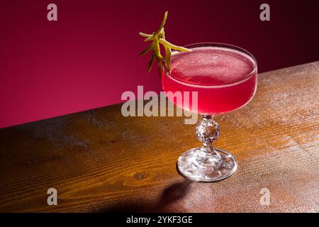 Un cocktail cosmopolite classique élégamment présenté dans un verre à pied en cristal, garni d'une touche de citron vert parfait pour les menus de bar, les guides de cocktails, ou Banque D'Images