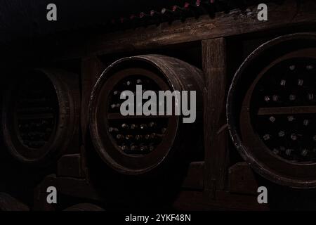 Cave à vin sombre et atmosphérique à Kakheti, Géorgie, avec des bouteilles de vin vieilli stockées dans de grands fûts en bois cette scène capture les traditionnels s. Banque D'Images