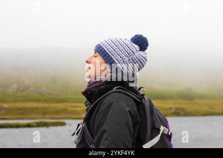 Paisible jeune randonneur prenant une profonde respiration avec les yeux fermés dans la contemplation brumeuse des îles Féroé, la pleine conscience, la liberté, la tranquillité et la détente Banque D'Images