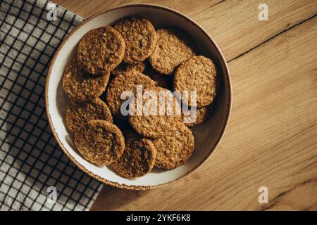 Vue de dessus de délicieux biscuits à grains entiers faits maison sur un bol rustique, placé sur une surface en bois avec un chiffon à carreaux à côté. Ces cookies sont suga Banque D'Images