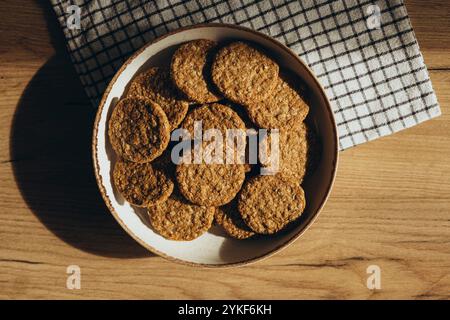 Vue de dessus de délicieux biscuits à grains entiers faits maison sur un bol rustique, placé sur une surface en bois avec un chiffon à carreaux à côté. Ces cookies sont suga Banque D'Images