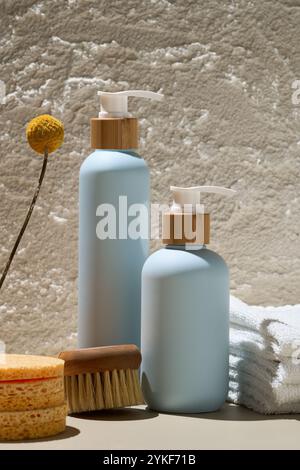 Élégantes bouteilles cosmétiques bleues associées à des bouchons en bois naturel, une fleur sèche et des essentiels de spa sur un fond texturé Banque D'Images