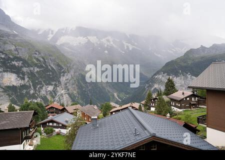 Une vue captivante depuis Lauterbrunnen, avec des montagnes brumeuses, des chalets suisses traditionnels et une végétation luxuriante dans un cadre alpin serein Banque D'Images