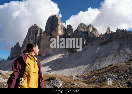 Une personne asiatique dans une veste admire les sommets imposants de Tre Cime di Lavaredo dans les Dolomites, Italie le paysage accidenté est baigné de soleil avec Banque D'Images