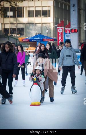 Patineurs mères et enfants sur glace à la patinoire du Bryant Park Winter Village 2024. Dans Midtown Manhattan près de la 42ème rue. L'enfant utilise une aide de patin pingouin Banque D'Images