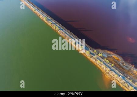 Une image aérienne de Riotinto, montre un contraste saisissant entre les réservoirs d'eau vert et rouge, séparés par une route les couleurs vibrantes et divi tranchant Banque D'Images
