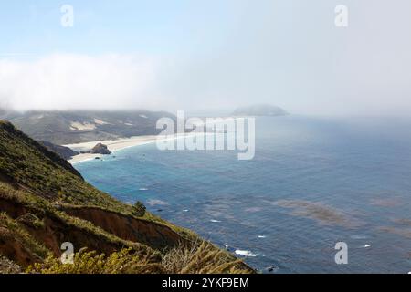 Une vue sereine sur la côte avec un océan brumeux, des plages de sable et des falaises escarpées sous un ciel brumeux la scène capture l'immensité et la tranquillité de la nature, Banque D'Images