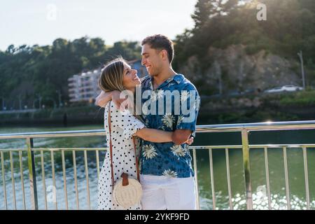 Un homme handicapé partage une étreinte aimante avec son partenaire à l'extérieur, ils se tiennent sur un pont, entouré de verdure, se prélasser dans la chaleur d'un da ensoleillé Banque D'Images