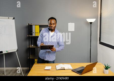 Homme debout dans le bureau regardant une tablette. Banque D'Images