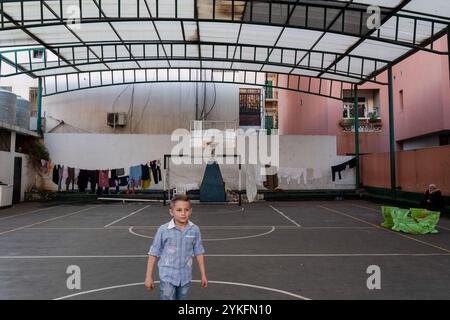 Beyrouth, Liban. 16 novembre 2024. Un garçon déplacé est vu jouer sur le terrain de basket d'une école transformée en abri à Beyrouth. Alors que la guerre entre le Hezbollah et Israël traîne, les autorités libanaises estiment que plus de 1,2 millions de personnes ont été déplacées à l'intérieur du pays. Crédit : SOPA images Limited/Alamy Live News Banque D'Images