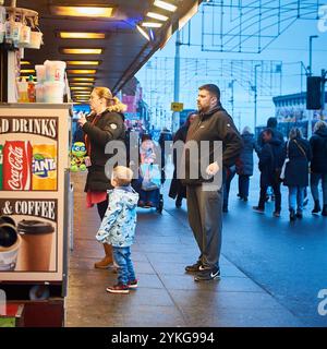 Jeune famille achetant des crèmes glacées sur Blackpool Golden Mile au crépuscule en hiver Banque D'Images