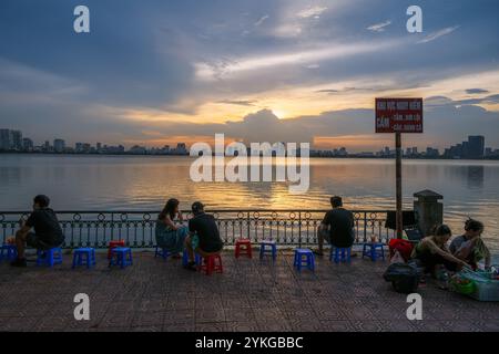 Ceci est une vue du célèbre lac de l'Ouest à Hanoi avec des gens assis au bord du lac regardant le coucher du soleil le 02 juillet 2023 à Hanoi, Vietnam Banque D'Images