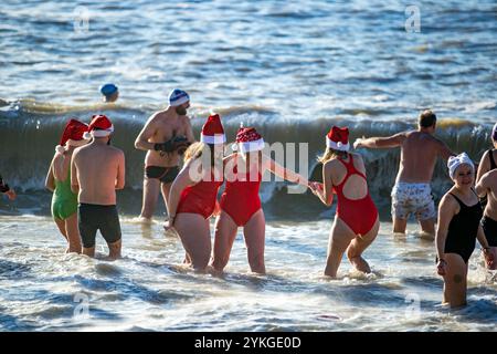 Brighton, Royaume-Uni. 25 décembre 2019. Des centaines de personnes se rassemblent sur la plage de Brighton pour leur baignade annuelle le jour de Noël. Malgré les préoccupations du conseil en matière de sécurité et les grosses vagues de la mer, plusieurs nageurs ont pris part à la baignade de Noël de cette année au large de la plage de Brighton dans leurs bikinis, shorts de bain et tenues du Père Noël Banque D'Images