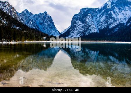 Les montagnes enneigées se reflètent sur le lac Dobbiaco au milieu des dolomites Banque D'Images