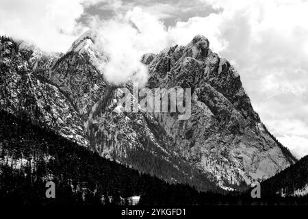 Sommets enneigés des dolomites avec des nuages et des pins autour du lac de Dobbiaco dans les Dolomites, Italie Banque D'Images