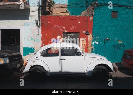 Guanajuato, Mexique - 6 février 2024 : une Coccinelle Volkswagen blanche classique garée contre un mur vif et altéré avec des graffitis à Guanajuato, Mexique, Banque D'Images