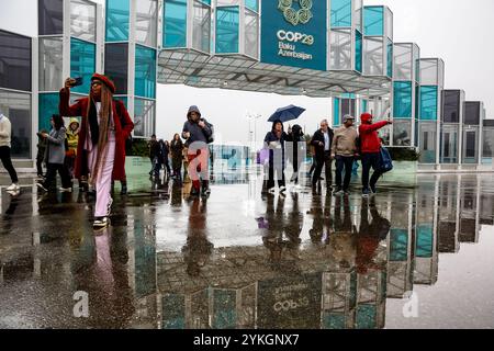 Bakou, Azerbaïdjan, le 18 novembre 2024. Les participants passent sous la pluie devant l'entrée principale du site de la Conférence des Nations Unies sur les changements climatiques COP29, un événement organisé par la CCNUCC au stade olympique de Bakou. La COP29, qui se déroule du 11 au 22 novembre, se concentre sur le financement climatique. Crédit : Dominika Zarzycka/Alamy Live News. Banque D'Images