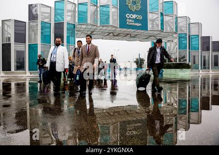 Bakou, Azerbaïdjan, le 18 novembre 2024. Les participants passent sous la pluie devant l'entrée principale du site de la Conférence des Nations Unies sur les changements climatiques COP29, un événement organisé par la CCNUCC au stade olympique de Bakou. La COP29, qui se déroule du 11 au 22 novembre, se concentre sur le financement climatique. Crédit : Dominika Zarzycka/Alamy Live News. Banque D'Images