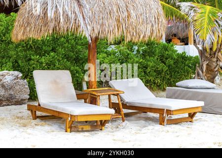Palapa toits de chaume palmiers parasols parasols parasols et chaises longues à l'hôtel balnéaire sur la plage tropicale mexicaine de Playa del Carmen Mexique Banque D'Images