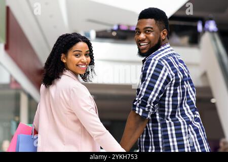 Loisirs pour couple. Black Man and Woman marchant dans le centre commercial, en tenant les mains Banque D'Images