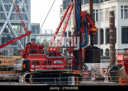 Les ouvriers de la construction utilisent des machines lourdes sur une plate-forme flottante à Middle Dock où le projet de réaménagement de transformation se poursuit au cœur du quartier financier de Canary Wharf, où les gens se détendent pendant leur journée de travail le 5 novembre 2024 à Londres, au Royaume-Uni. Canary Wharf est une zone située près de l'île des chiens dans le quartier londonien de Tower Hamlets et est définie par la Greater London Authority comme faisant partie du quartier central des affaires de Londres. Avec la City de Londres, elle constitue l'un des principaux centres financiers du Royaume-Uni et du Banque D'Images