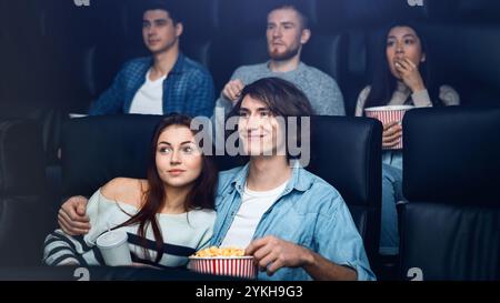 Ensergeant dans le cinéma. Un joli couple de jeunes qui apprécient leur date dans le cinéma Banque D'Images