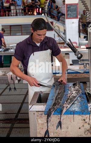 Poissonnier filant du sabre noir au marché aux poissons de Madère Banque D'Images