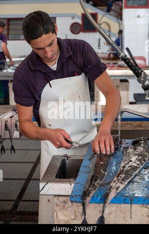 Poissonnier filant du sabre noir au marché aux poissons de Madère Banque D'Images