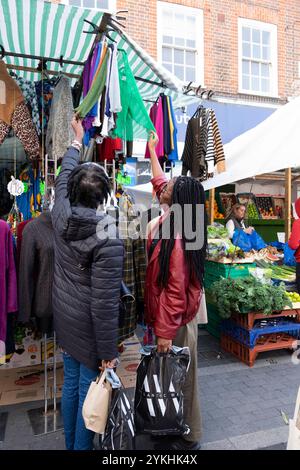 Vue arrière de deux femmes regardant des foulards sur le stand de vêtements dans Brixton Market Street octobre 2024 Londres Angleterre Royaume-Uni KATHY DEWITT Banque D'Images