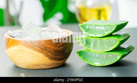 Dans l'image, vous pouvez voir des feuilles de la plante d'aloe vera et de petits morceaux de sa pulpe sur un fond d'ardoise Banque D'Images