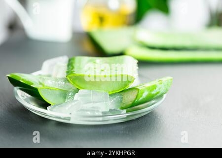 Dans l'image, vous pouvez voir des feuilles de la plante d'aloe vera et de petits morceaux de sa pulpe sur un fond d'ardoise Banque D'Images