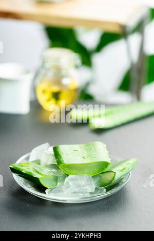 Dans l'image, vous pouvez voir des feuilles de la plante d'aloe vera et de petits morceaux de sa pulpe sur un fond d'ardoise Banque D'Images