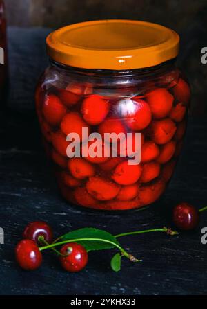 Conserves de cerises faites maison. Cerises fraîches dénoyautées dans du sirop de sucre dans un bocal en verre. Nourriture biologique en conserve du jardin. Banque D'Images