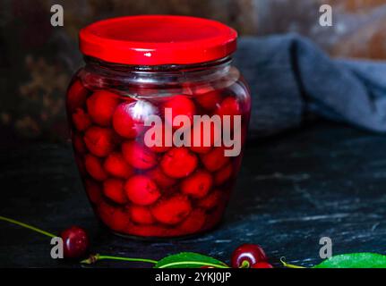 Conserves de cerises faites maison. Cerises fraîches dénoyautées dans du sirop de sucre dans un bocal en verre. Nourriture biologique en conserve du jardin. Banque D'Images