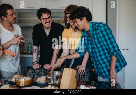 Amis profitant d'une séance de cuisine dans une cuisine moderne Banque D'Images