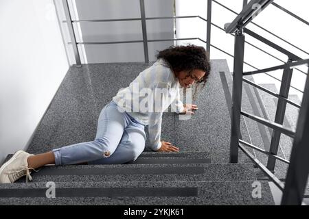 Femme blessée dans les escaliers dans le bâtiment après la chute. Accident dangereux Banque D'Images