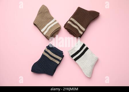 Différentes chaussettes confortables sur fond rose clair, pose plate Banque D'Images