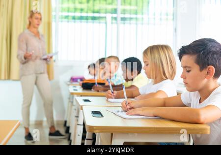 Diligent tweens étudiant en classe avec une enseignante Banque D'Images