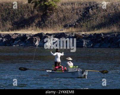 Femme pêchant à la mouche dans la rivière Missouri dans le Montana tout en se tenant debout dans un bateau ramé par un homme. Ils sont photographiés par derrière. Banque D'Images