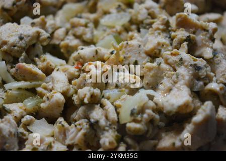 Préparation des aliments, petits morceaux de poulet avec des oignons blancs frits, cuits dans une poêle en métal noir. Banque D'Images