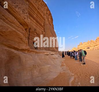 Touristes regardant la tombe 45 à Jabal AlBanat (Qasr AlBint), site archéologique de Hegra (al-Hijr / Madā ͐ à Ṣāliḥ), dans le désert près d'Al Ula, Arabie Saoudite Banque D'Images