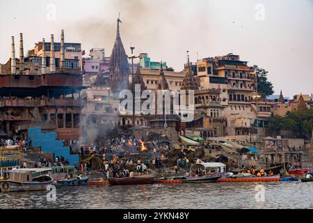 Vue sur les ghats brûlants à varanasi avec la fumée qui monte, les bateaux à proximité, et les bâtiments anciens Banque D'Images