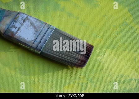 Un pinceau à peindre reposant sur des couches acryliques vertes texturées, mettant en valeur la créativité Banque D'Images