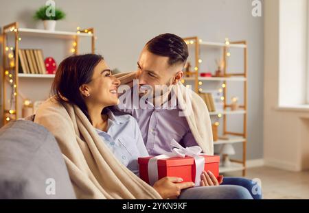Couple aimant avec boîte cadeau assis et passer du temps ensemble, célébrant la Saint-Valentin à la maison. Banque D'Images
