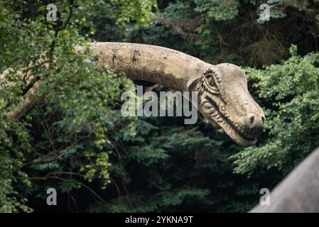 Gros plan d'une sculpture de dinosaure dans un parc, mettant en valeur son design détaillé, ses couleurs vives et son apparence réaliste, mêlant créativité et paleon Banque D'Images